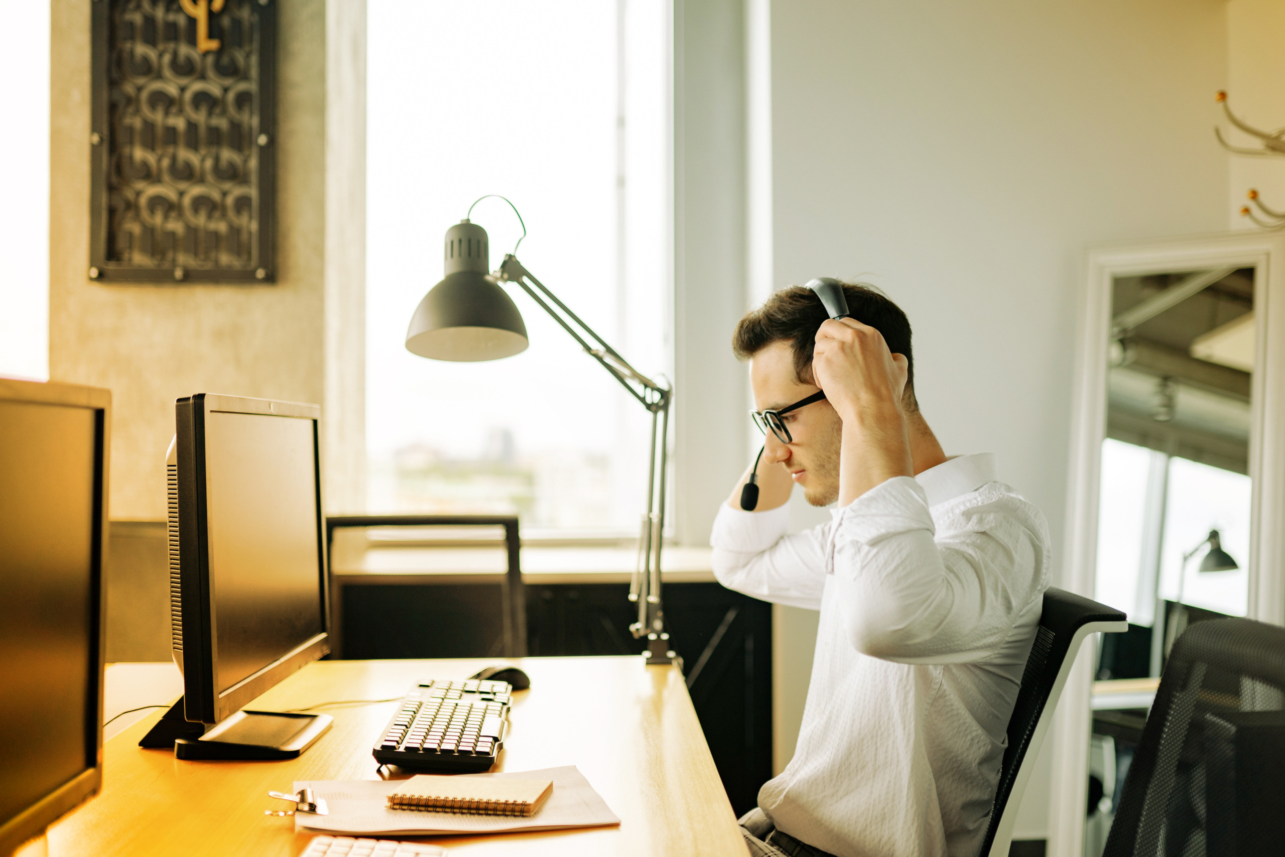 Salarié qui prend un appel téléphonique en visio devant son ordinateur.