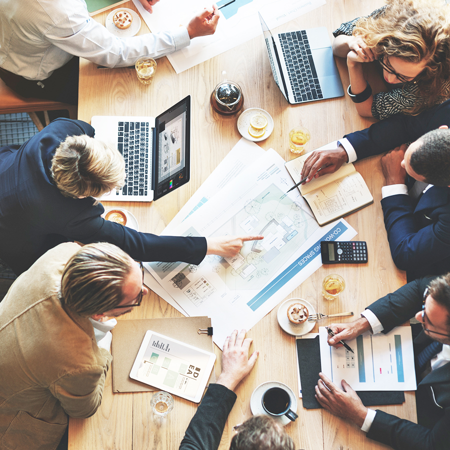 Réunion de travail d'une équipe avec les ordinateurs et des plans de travail, qui montrent la dématérialisation des documents lors d'une réunion.